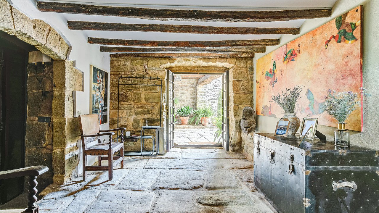 Entrada de la masía con suelo de piedra y obras de arte