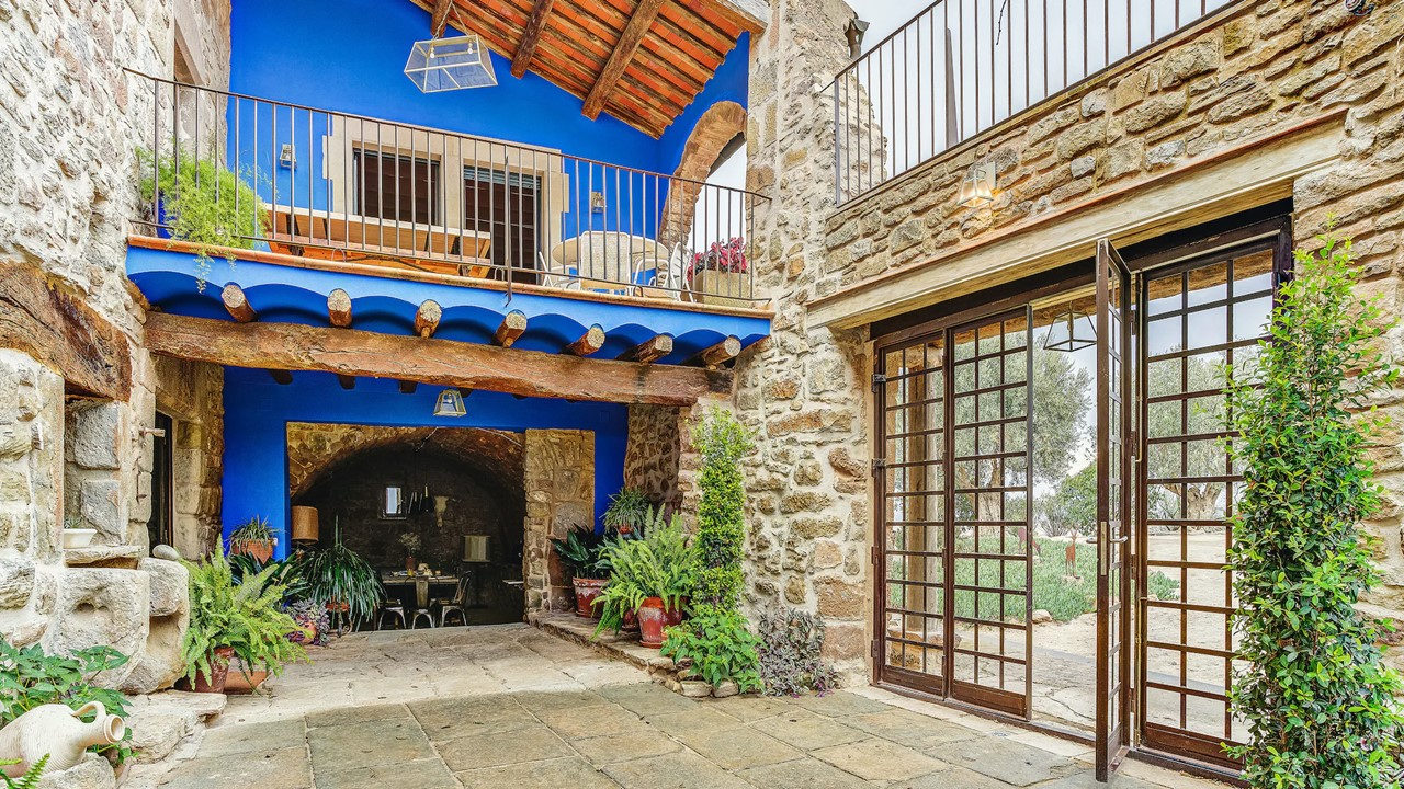 Patio con balcón azul de la Masia de Queralt