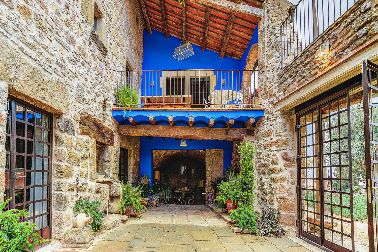Patio interior de piedra de la Masia de Queralt con la fachada azul