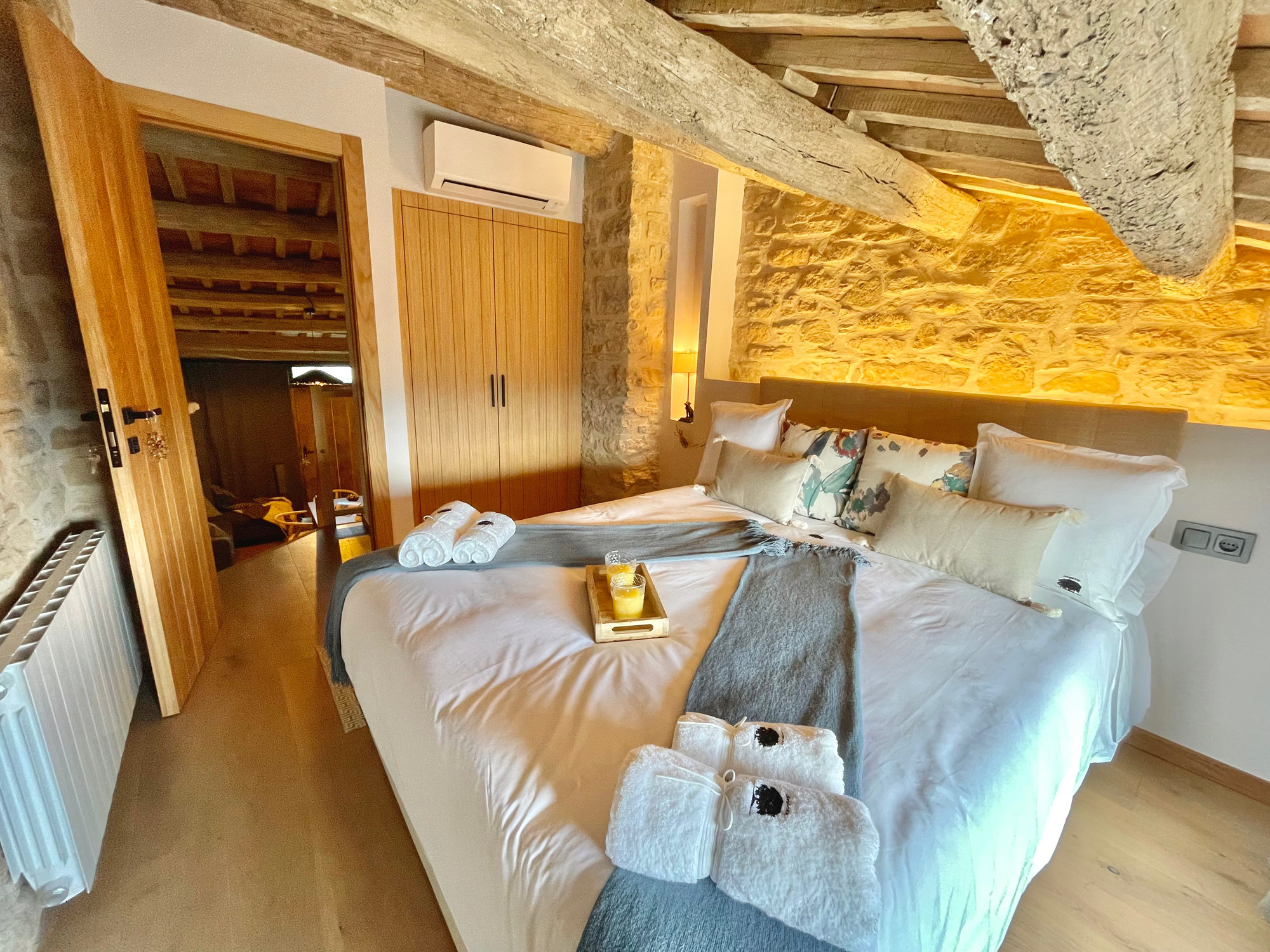 Dormitorio de la Torre de Queralt con paredes de piedra y techo de madera