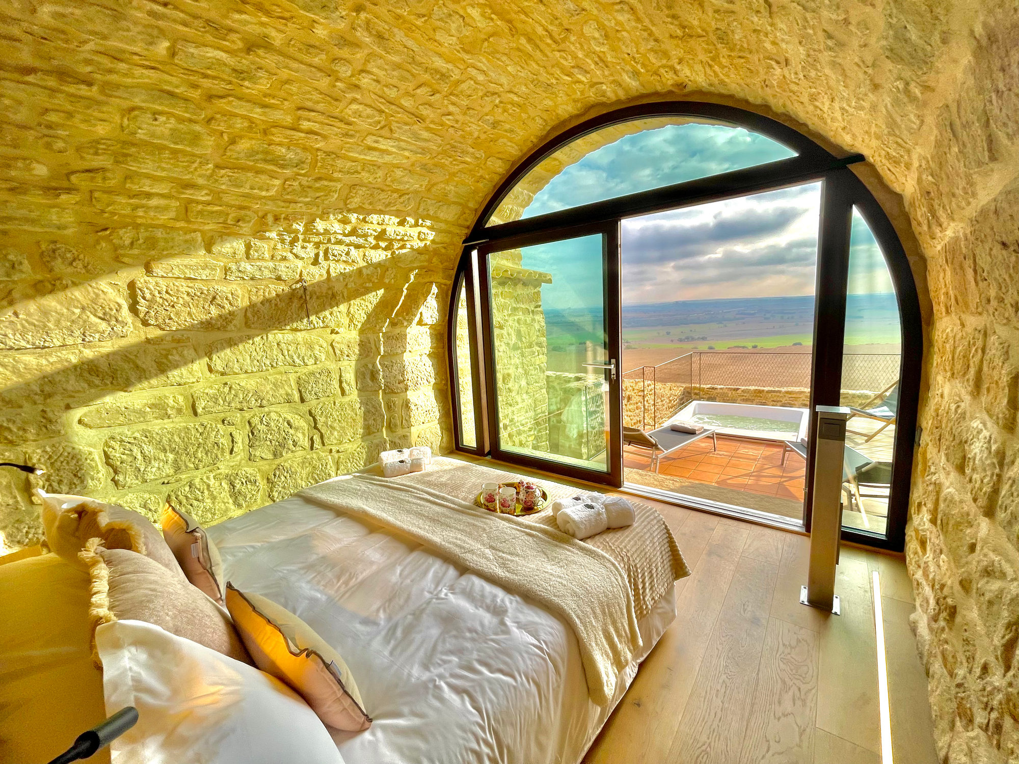 Habitación romántica de la Torre de Queralt con ventanal en arco al amanecer